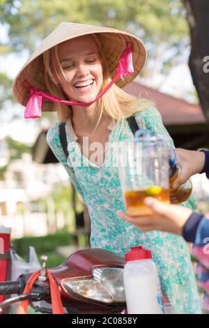 Eine lächelnde Frau, die einer Dame an einem Saftstand in asien zuschaut, die auf der Straße einen frischen Saft zubereitet. Stockfoto