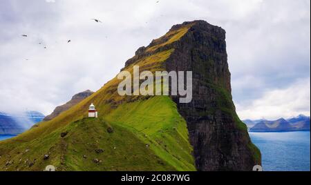 Kleiner Leuchtturm auf der Insel Kalsoy mit Möwen fliegen, Färöer Inseln Stockfoto