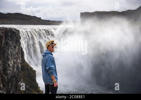 Wanderer, der am Rande des Dettifoss Wasserfalls in Island steht Stockfoto