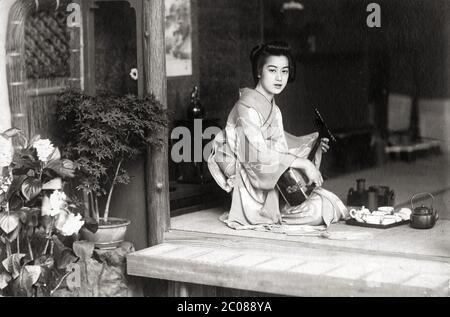 [ 1920er Jahre Japan - Shamisen spielen ] - EINE japanische Frau, die den Shamisen spielt, ein traditionelles japanisches Musikinstrument mit drei Saiten, ca. 1923 (Taisho 12). Silberdruck mit Vintage-Gelatine aus dem 20. Jahrhundert. Stockfoto