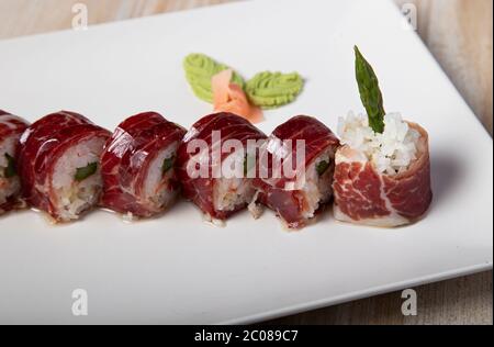 Japanischer Uramaki Teller mit Eichelschinken und Spargel. Isoliertes Bild. Stockfoto