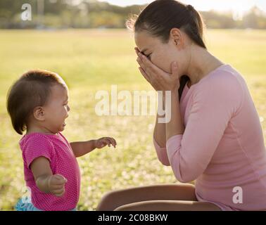 Überwehte unglückliche Mutter weiß nicht, wie sie sich um ihr weinendes Baby im Park kümmern soll. Postpartale Depression. Stockfoto