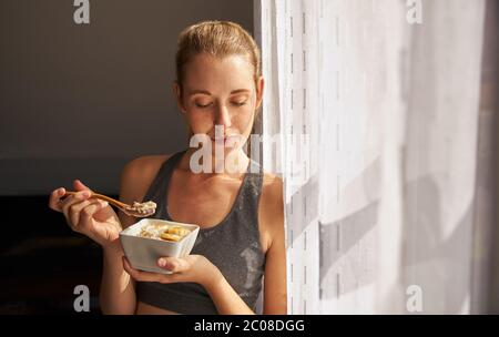 Junge Frau hält gesunde Frühstückschüssel mit Hafer und Obst. Stockfoto