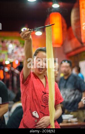 Xian / China - 3. August 2015: Restaurantangestellte Frau bereitet berühmte Xian Nudeln im muslimischen Viertel der Altstadt von Xian in der Provinz Shaanxi, Chi Stockfoto