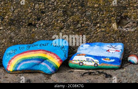 Port Seton, East Lothian, Schottland, Großbritannien. Juni 2020. Covid-19 Pandemiesymbole von Einheimischen: Eine hunderte Meter lange Linie an der Strandpromenade mit bunten und kreativen handbemalten Steinen mit inspirierenden Botschaften. Es scheint ein Phänomen zu sein, das sich in den Städten und Dörfern von East Lothian verbreitet. Steine mit einem Regenbogen Symbol der Hoffnung und einer Darstellung Rettungsdienste einschließlich RNLI Rettungsboot und die Küstenwache Such-und Rettungsdienst mit einem Hubschrauber Stockfoto