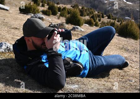 Professioneller Fotograf am Boden, nimmt Bild der Berglandschaft Stockfoto