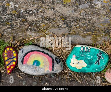 Port Seton, East Lothian, Schottland, Großbritannien. Juni 2020. Covid-19 Pandemiesymbole von Einheimischen: Eine hunderte Meter lange Linie an der Strandpromenade mit bunten und kreativen handbemalten Steinen mit inspirierenden Botschaften. Es scheint ein Phänomen zu sein, das sich in den Städten und Dörfern von East Lothian verbreitet. Steine mit Regenbogen und ein Golfer spielen ein Loch in einem auf einem Golfplatz Stockfoto