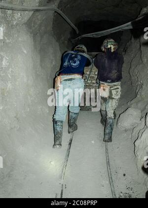 Zwei Bergleute schieben den Bergbauwagen in den Silberminen von Potosi Stockfoto