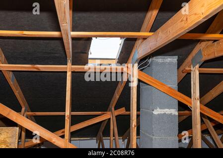 Dachboden mit sichtbaren Dachstühlen, Dachluke für einen Schornsteinfeger und mit Systemkamin. Stockfoto