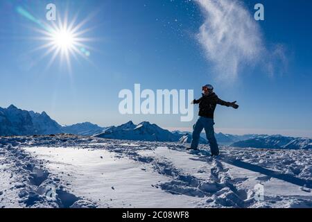 Mädchen genießen Sonnenstrahlen im Winter, während Schneefall in der Luft auf der Spitze der Bergkette. Snowboarder am späten Nachmittag in den Schweizer alpen im Winter Stockfoto