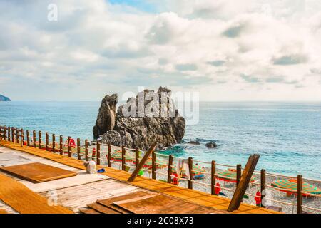 Sonnenschirme säumen den Sandstrand der Spiaggia di Monterosso al Mare in der Nähe der grossen Rock im Dorf Monterosso al Mare Italien, Teil der Cinque Terre Stockfoto