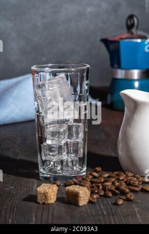 Hohes Glas mit Eis für die Zubereitung von Eiskaffee, Geysir-Kaffeemaschine auf dem Hintergrund, Stockfoto