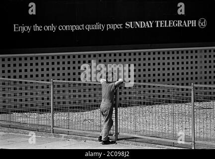 AJAXNETPHOTO. JUNI 1968. PORTSMOUTH, ENGLAND. - DIE WELT BEOBACHTEN - EIN JUNGER MANN LEHNT SICH AN EINEN ZAUN IN DER NÄHE DER FRATTON-EISENBAHNBRÜCKE; IM HINTERGRUND WIRBT EIN HORTER FÜR 6 PENCE FÜR EINE NATIONALE SONNTAGSZEITUNG. (6D VOR DEZIMALPREIS ODER EIN TANNER.). FOTO: JONATHAN EASTLAND/AJAX REF:3568156 19A Stockfoto