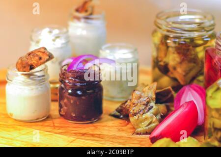 Italienische Vorspeisen, Trüffelbutter, Sardellenbutter, aromatische Kräuterbutter, Artischocken in Öl, eingelegte Gurken, süße und saure Zwiebeln, Zwiebelmarmelade. Stockfoto