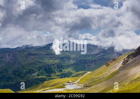 Österreichische Alpen unter weißem bewölktem Himmel und gelben Sonnenstrahlen am Morgen Stockfoto