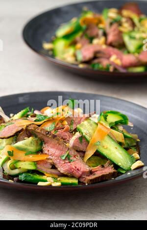 Vertikale Ansicht von 2 Platten mit asiatischem Rindfleischsalat. Inspiriert von thailändischen und vietnamesischen Salaten, verpackt mit frischem, gesundem Gemüse. Stockfoto