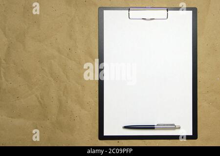 Ein Tablett mit einem weißen Blatt im A4-Format mit Stift auf einem beigen Bastelpapier. Konzept der Analyse, des Studiums, der aufmerksamen Arbeit. Stock Foto mit leerem Platz für Ihren Text und Design. Stockfoto