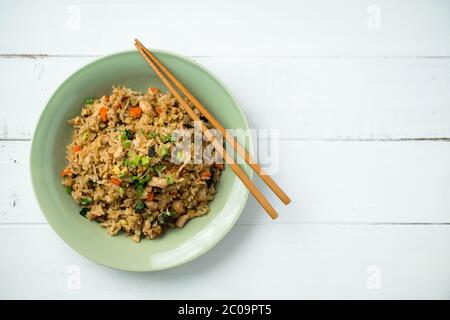 Gebratener Reis Ansicht von oben auf weißem Hintergrund. Teller gebratenen Reis mit Essstäbchen auf der Seite. Dieses asiatisch inspirierte Rezept verwendet viele frische Zutaten. Stockfoto