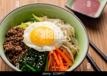 Bibimbap ist ein klassisches koreanisches Gericht. Eine Schüssel Reis wird mit gewürztem Gemüse, Fleisch und einer sonnigen Seite oben Spiegelei auf gekrönt. Stockfoto