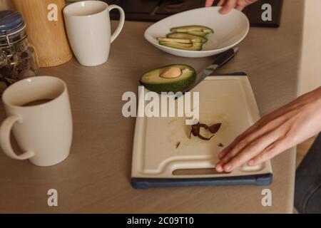 Ansicht der Frau, die in der Nähe von schmackhaften Avocado auf dem Schneidebrett steht Stockfoto