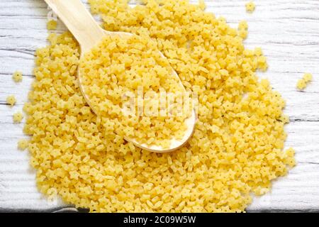 Holzlöffel mit Nudeln. Ungekochte Pasta in Form von Sternen Stockfoto