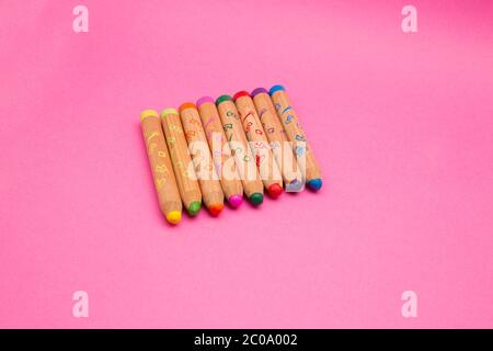 Mehrere bunte Holzkreiden isoliert auf rosa Hintergrund mit Copy Space farbige Zeichenstifte für Kinder, close up Stockfoto
