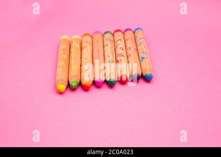 Mehrere bunte Holzkreiden isoliert auf rosa Hintergrund mit Copy Space farbige Zeichenstifte für Kinder, close up Stockfoto
