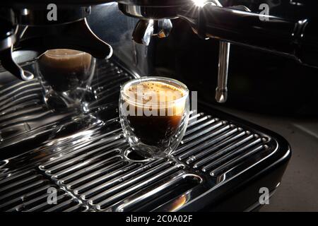 Frisch gebrühter cremiger Espresso in einer transparenten Kaffeetasse, die auf einer manuellen Kaffeemaschine aus nächster Nähe platziert wird Stockfoto