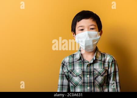 asiatische junge in medizinischen Maske auf gelb während der Selbstisolation Stockfoto