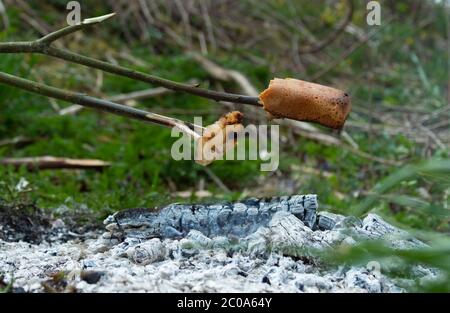 Gegrillter Speck und Brot am Lagerfeuer während des Campens im Freien. Stockfoto