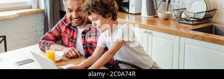 Panorama-Orientierung von fröhlichen Kind mit Laptop in der Nähe Freelancer Vater Stockfoto