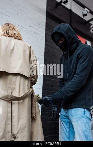 Low-Winkel-Ansicht des Räubers in der Sturmhaube Bargeld in der Nähe der Frau Stockfoto