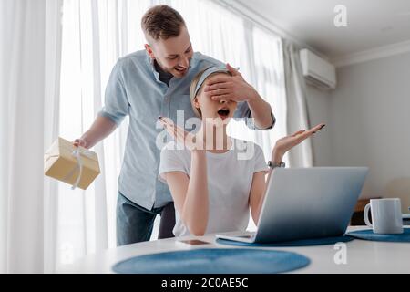 Schöner Mann Augen der überraschten Freundin während der Holding präsentieren Stockfoto