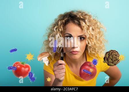 Mädchen ist misstrauisch über die Ansteckung von Bakterien auf Lebensmitteln. Cyanfarbener Hintergrund Stockfoto