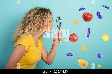 Mädchen ist misstrauisch über die Ansteckung von Bakterien auf Lebensmitteln. Cyanfarbener Hintergrund Stockfoto