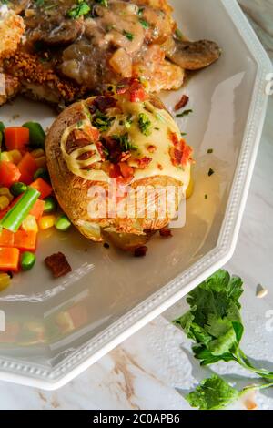 Deutsche Mandelchick-Jagerschnitzel mit beladen gebackenen Kartoffeln und Gemüse Stockfoto