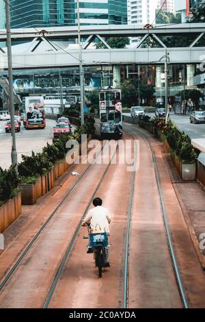 Mann auf einem Fahrrad fahren in der Gegend gewidmet Doppeldecker-Straßenbahnen in Hongkong China Stockfoto