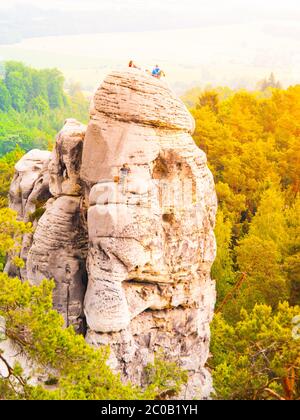 Felskletterer auf Sandsteinturm. Einer steigt hinauf und zwei sitzen oben. Bouldern in Böhmisches Paradies, aka Cesky Raj, Tschechische Republik, Europa. Stockfoto