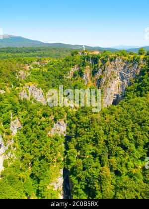 Blick auf die tiefe Schlucht des Flusses Reka und Dorf mit ländlichen Kirche, Skocjan Höhlen, Slowenien Stockfoto