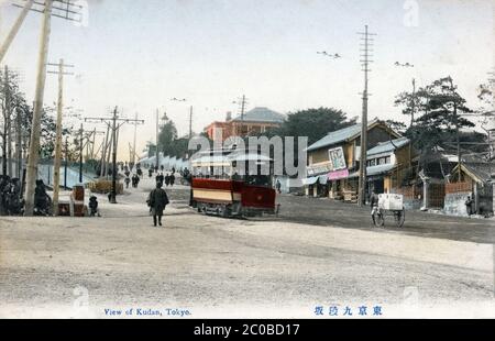 [ 1910 Japan - Tokyo Streetcar ] - Menschen und ein Straßenauto in Kudanzaka (九段坂) in Tokio. Der Turm auf dem Hügel ist der Leuchtturm (燈明台), der 1871 (Meiji 4) für Fischerboote in der Bucht von Tokio gebaut wurde. Vintage-Postkarte des 20. Jahrhunderts. Stockfoto