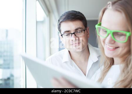 Glückliche Geschäftsleute, die im Büro mit einem Tablet-PC arbeiten Stockfoto