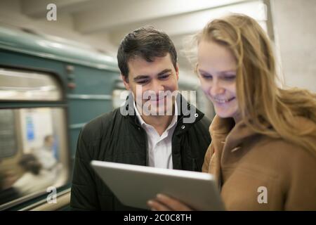 Glückliche junge Leute mit Touchpad in der U-Bahn Stockfoto