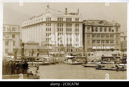 [ 1920er Jahre Japan - Kobe Port ] - Hafen startet am Meriken Hatoba (American Landing Pier), seit vielen Jahren der Hauptpier in Kobe. Im Hintergrund ist der Bund (Kaigandori). Das große weiße Gebäude ist das Osaka Shosen Kaisha Gebäude. Das Gebäude auf der rechten Seite mit den Markisen, ist das Oriental Hotel auf 6 Kaigandori. Vintage-Postkarte des 20. Jahrhunderts. Stockfoto