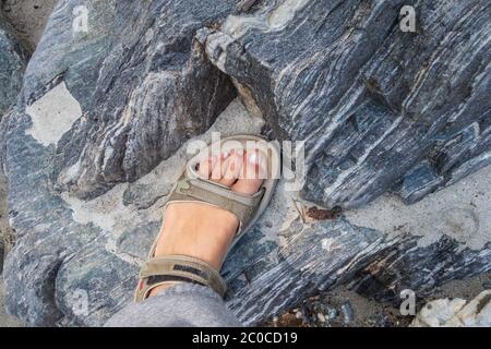 Frauen gebräunte Beine in offenen Sport-Sandalen auf einer Wanderung im Sommer. Reisekonzept, das Konzept Wandern Stockfoto
