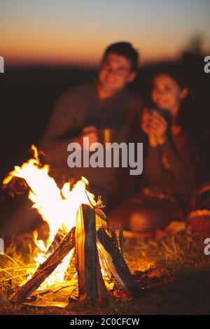 Porträt des glücklichen Paares sitzen durch einen Brand am herbstlichen Strand in der Nacht Stockfoto