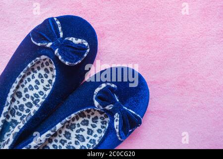 Blaue Pantoffeln mit Leoparden auf einem flauschigen rosa Teppich. Heim Damen- oder Kinderkleidung. Das Konzept von Wärme und Komfort zu Hause. Selektiver Fokus. Stockfoto