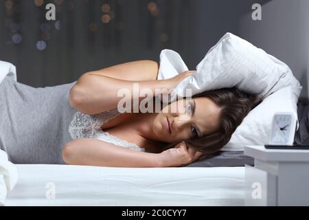 Wütende Frau leiden für Nachbar Lärm und Suchen an der Kamera liegen auf einem Bett in der Nacht zu Hause Stockfoto