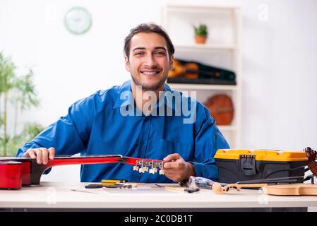 Junger Mann Reparatur der Gitarre Stockfoto
