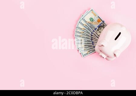 Sparschwein und Bargeld einhundert Dollar-Rechnungen auf rosa Hintergrund. Flaches Lay, Draufsicht, Overhead, Mockup, Schablone Stockfoto