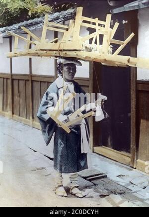 [ 1900s Japan - Female Porter ] - EINE japanische weibliche Porterin balanciert eine Leiter und Bänke auf ihrem Kopf. Vintage-Glasrutsche aus dem 20. Jahrhundert. Stockfoto